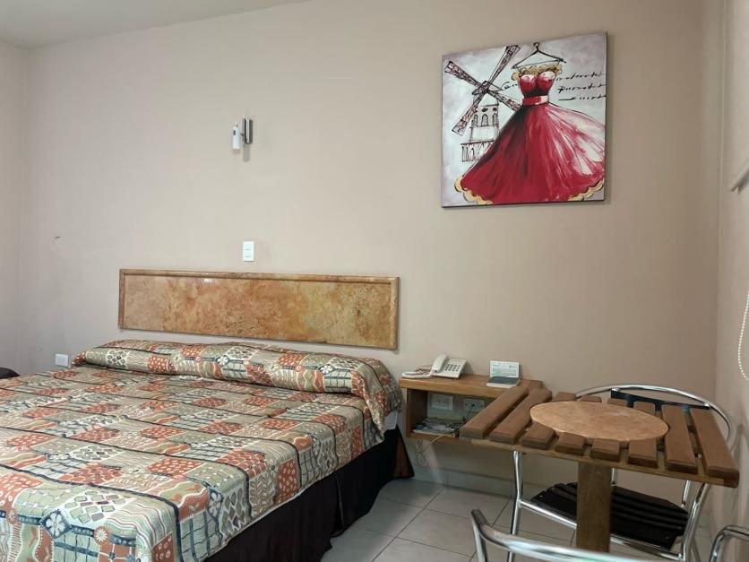 比亚埃尔莫萨Hotel Santo Domingo Express的卧室配有一张床和一张桌子,墙上挂着一张照片