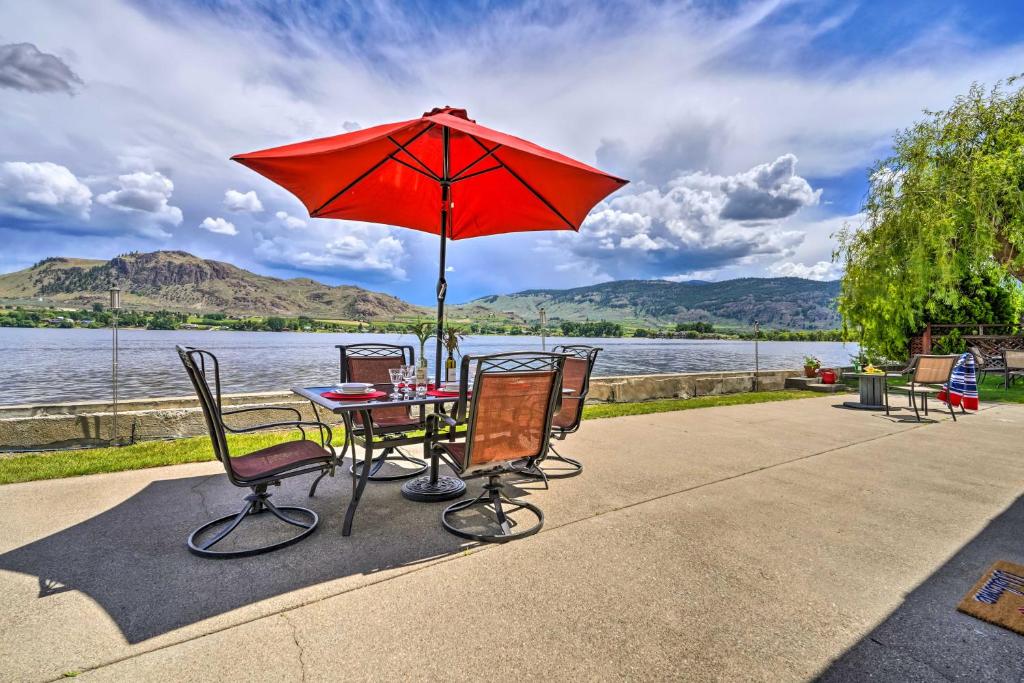 OrovilleWaterfront Osoyoos Lake Cottage with Beach and Patio!的一张桌子和椅子,配有红色雨伞