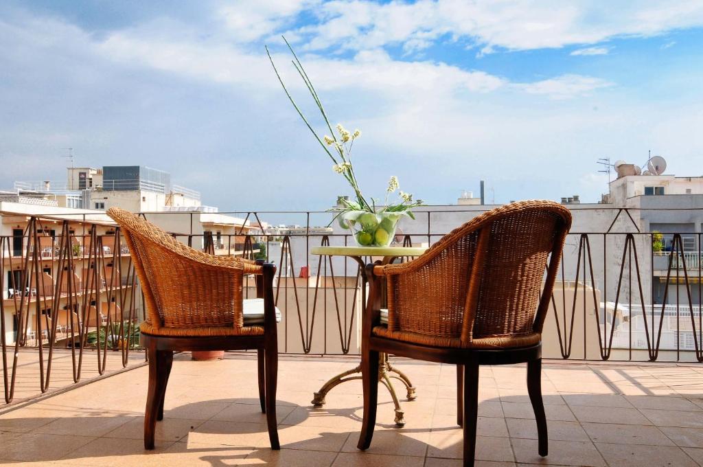 坎帕斯蒂利亚巴利阿尔酒店的阳台上配有两把椅子和一张桌子,花瓶上放着鲜花