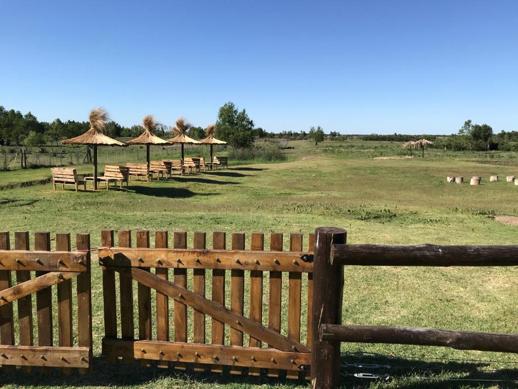 圣佩德罗El Nopal - Alojamiento的田野上有许多桌子和遮阳伞的木栅栏