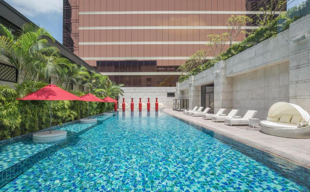 台中市台中林酒店的一座带椅子和遮阳伞的游泳池位于一座建筑旁边
