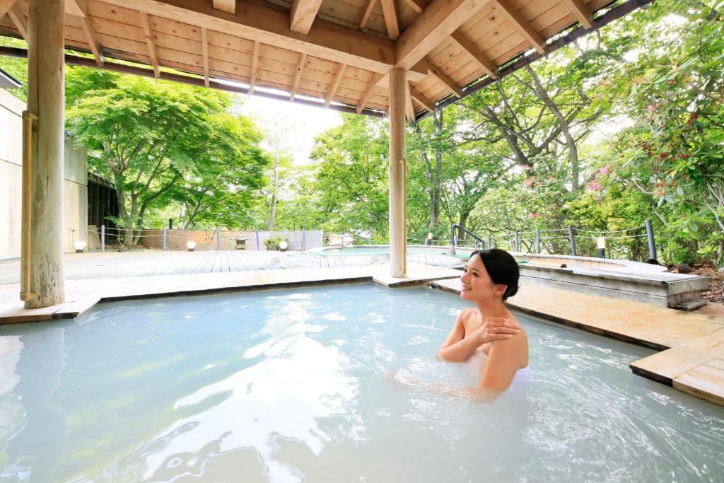 日光四季彩酒店(Hotel Shikisai)的坐在游泳池里的女人