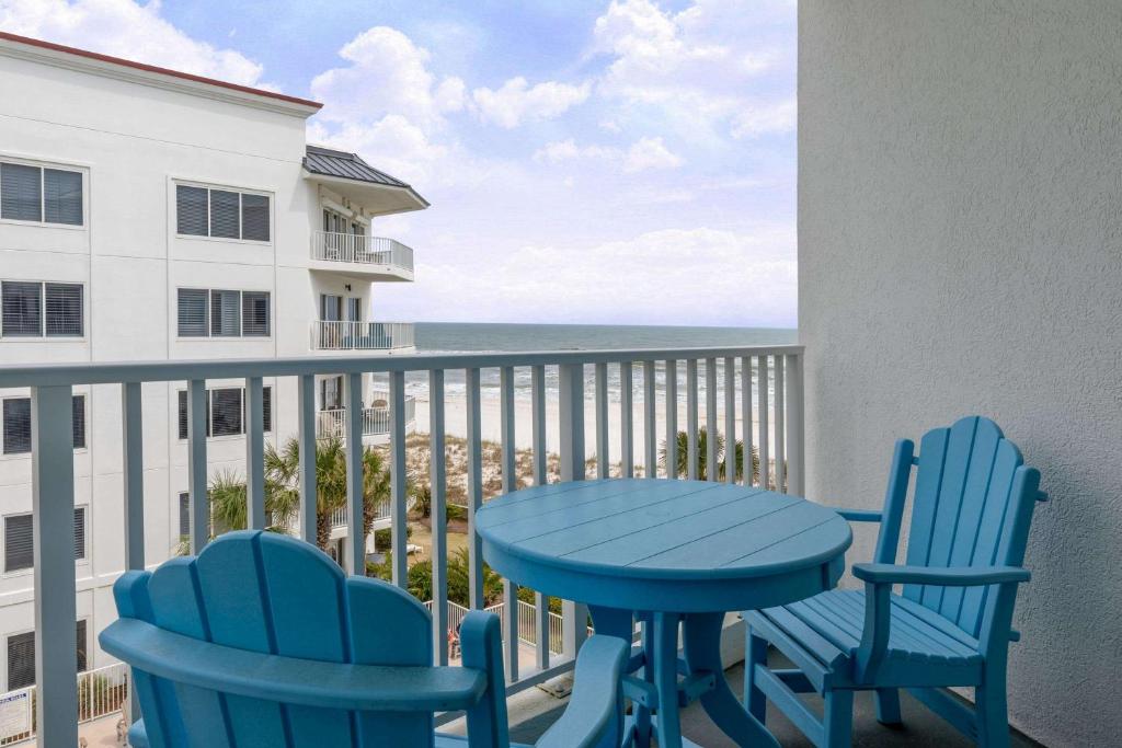 奥兰治比奇Palm Beach Resort Orange Beach a Ramada by Wyndham的阳台上的蓝色桌椅