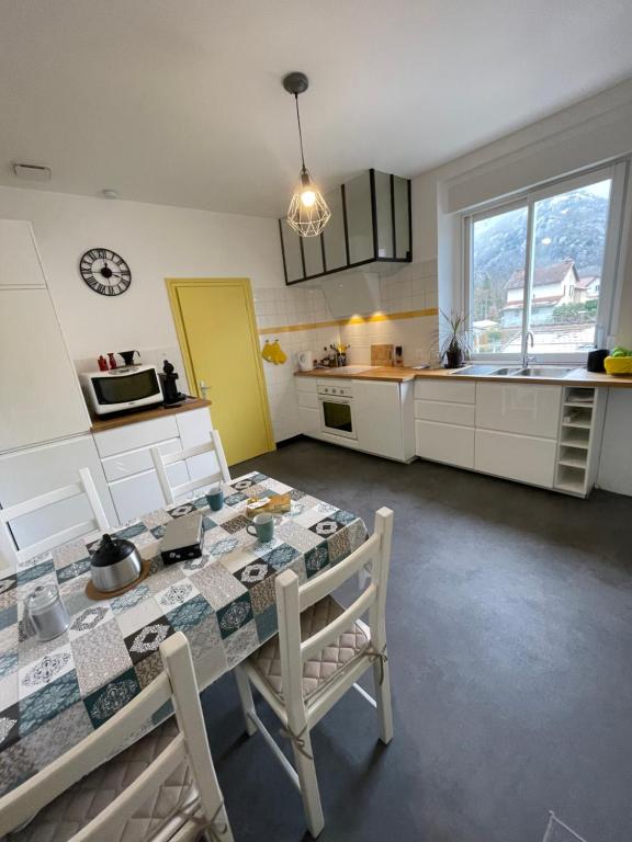 阿列日河畔的塔拉斯孔Appartement Tarascon sur Ariège的厨房配有桌椅和墙上的时钟