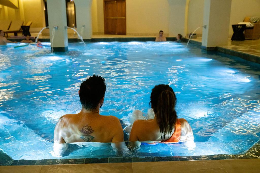 格拉玛多Buona Vitta Gramado Resort & Spa by Gramado Parks的坐在游泳池里的男人和女人
