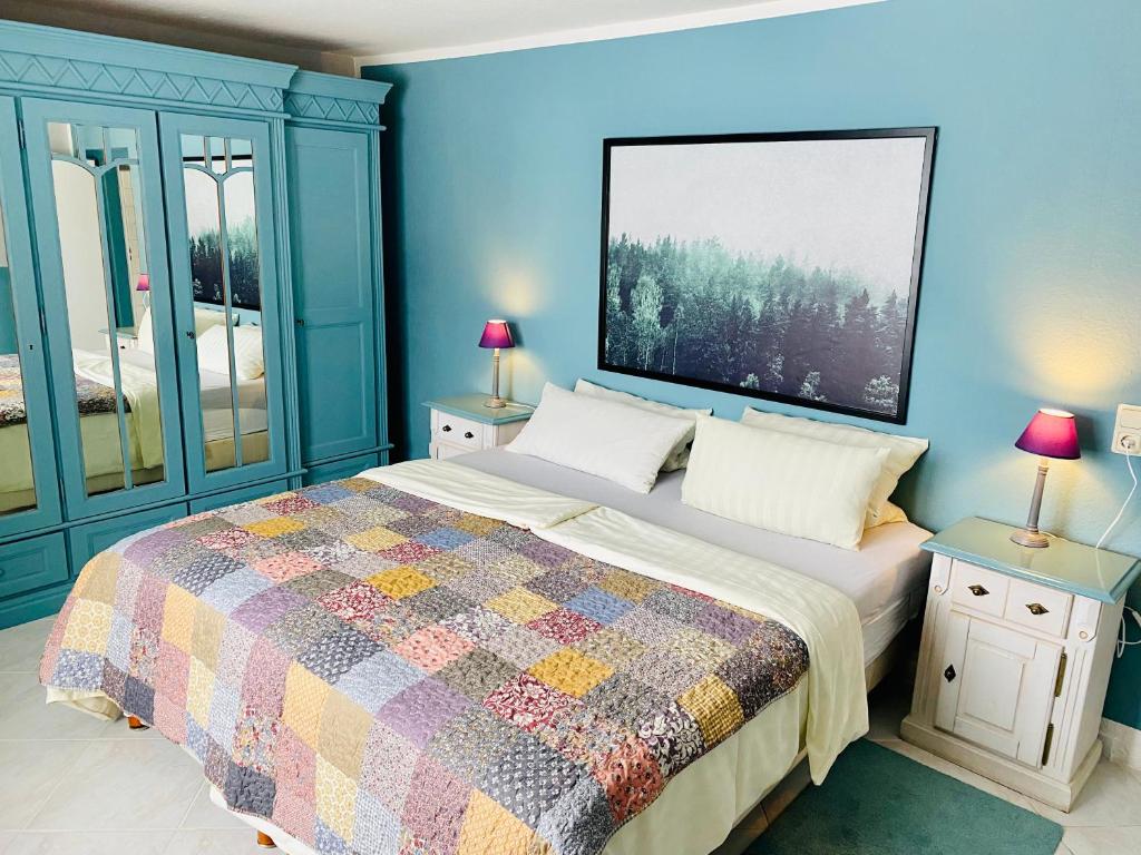 GroßbreitenbachFeWo hohetanne1的蓝色卧室,配有一张带五颜六色被子的床