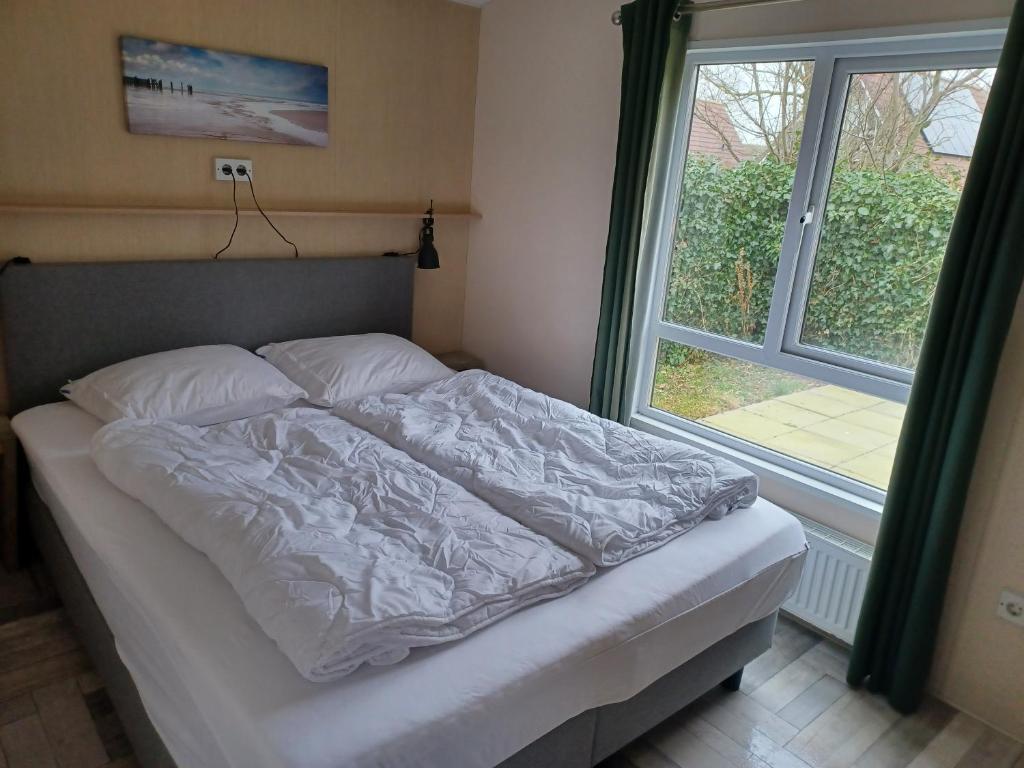 德科克斯多普Chalet duunzicht Texel的窗户旁卧室的一张床位