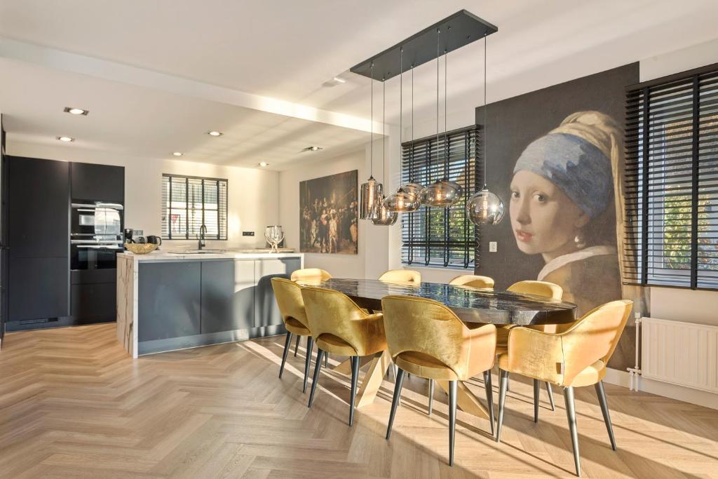 卡兰茨奥赫Villa Vermeer的厨房以及配有女性画作的用餐室