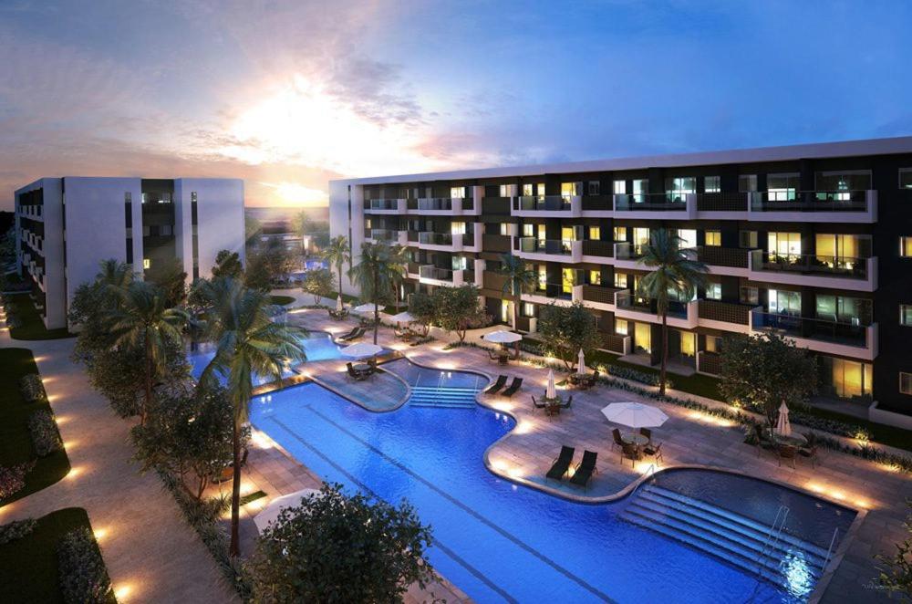 嘎林海斯港Mana Beach Resort Muro Alto Prime - Porto de Galinhas的一座大型建筑,晚上设有游泳池