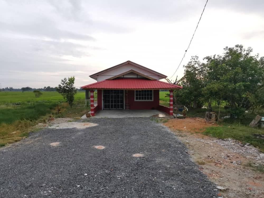 HomeStay Abah Alor Pongsu的一座红色的小建筑,在田野上有一个红色的屋顶