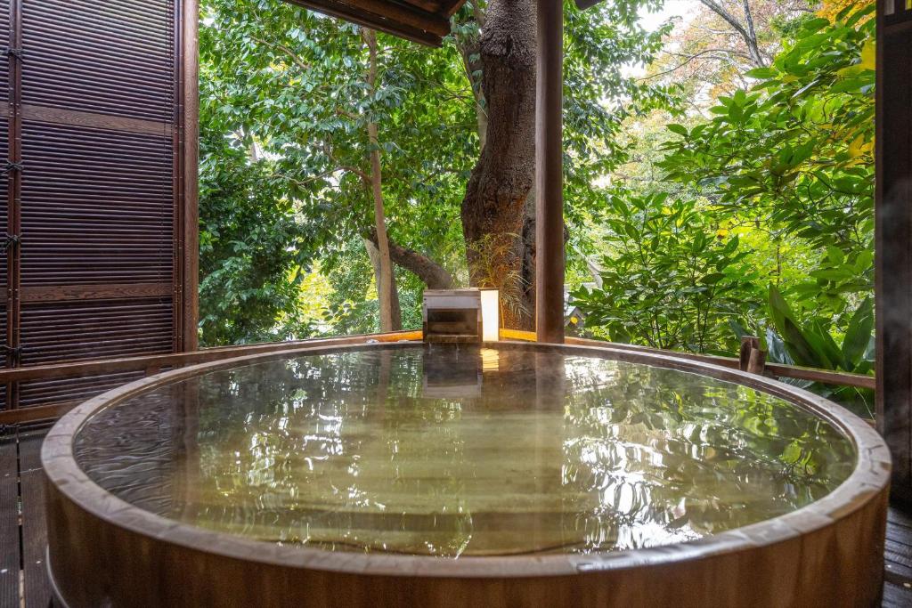 秦野市Jinya Ryokan的树底甲板上的热水浴池