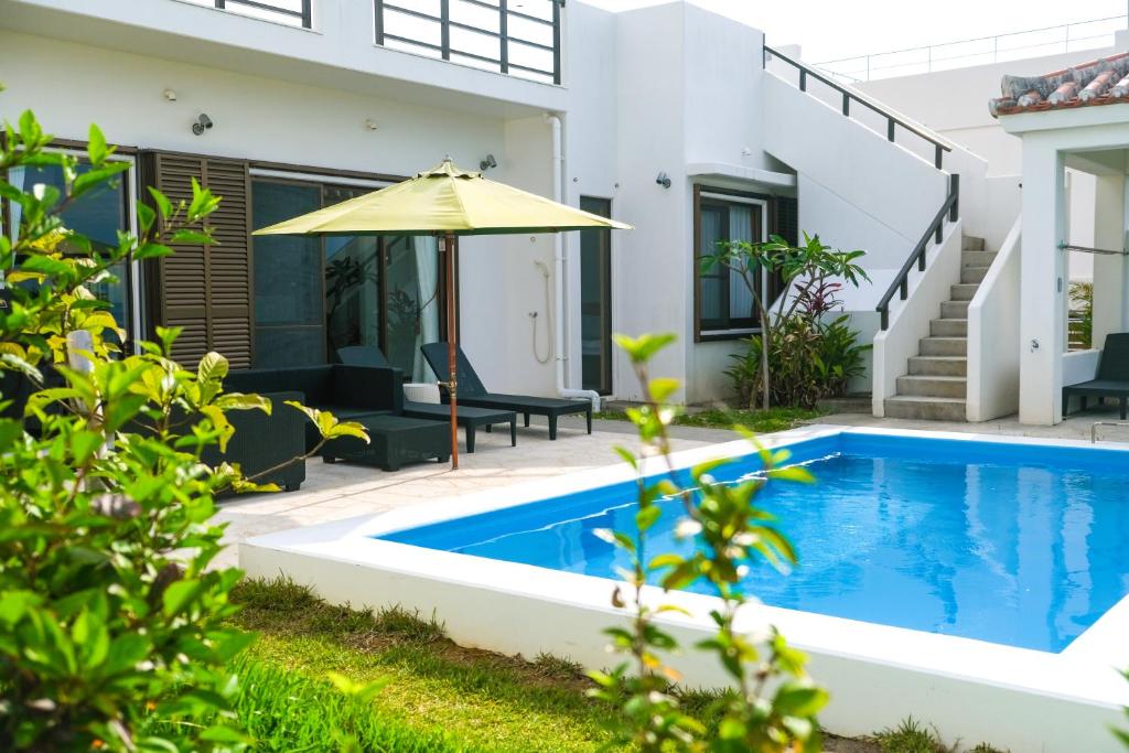 石垣岛Blue Ocean Resort的一座房子旁带遮阳伞的游泳池
