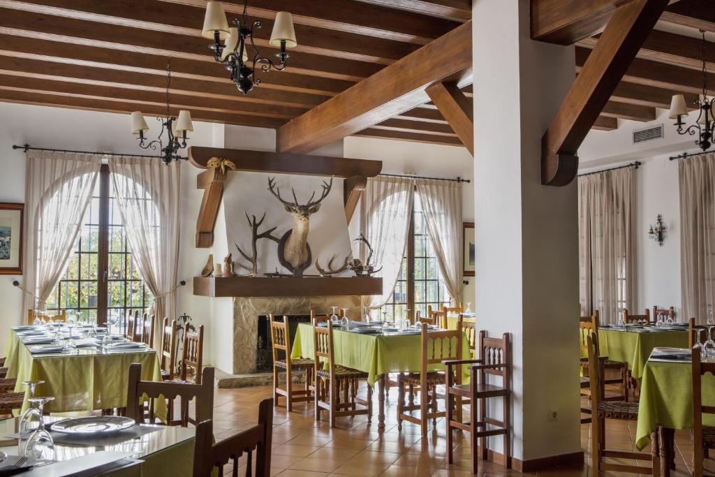 阿尔加尔Hotel Tugasa Villa de Algar的用餐室设有绿色桌椅和窗户。