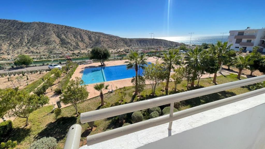 塔哈佐特Appartement vue sur piscine et sur mer的阳台享有游泳池和棕榈树的景致。