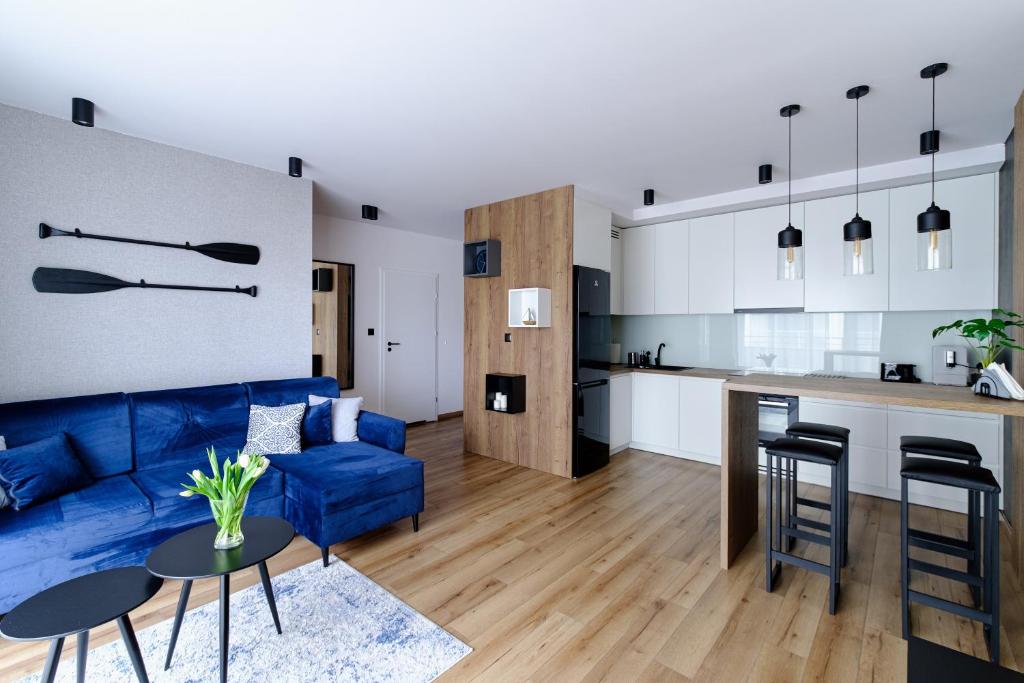 雷达Apartament Marynarska Aquapark的一间带蓝色沙发的客厅和一间厨房
