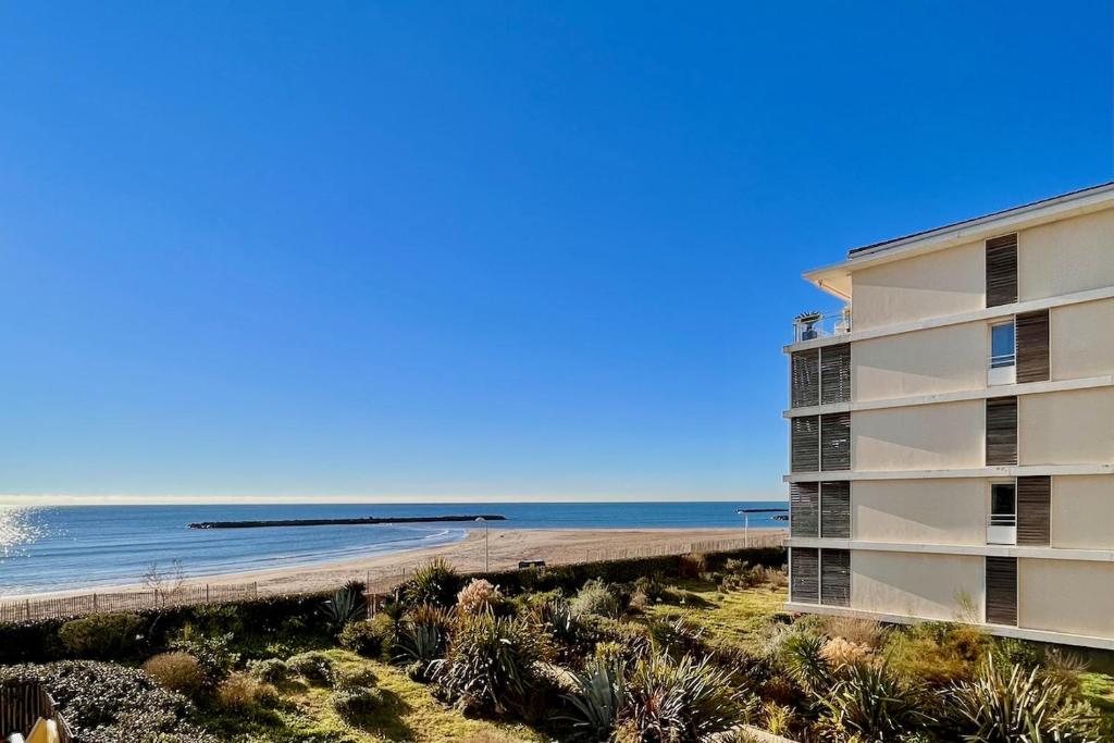 帕拉瓦莱弗洛Le Sunlight - T2 bord de mer, Parking的海滩上的建筑,以海洋为背景