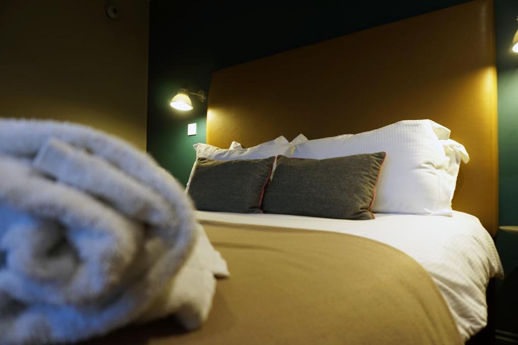 伯克翰斯特德The Penny Farthing Hotel的一间卧室配有带白色床单和枕头的床。