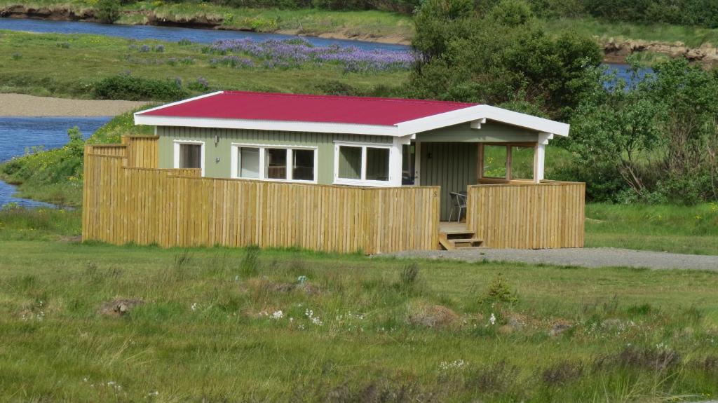 DrangsnesHvammur 5 with private hot tub的田野上带红色屋顶的小房子