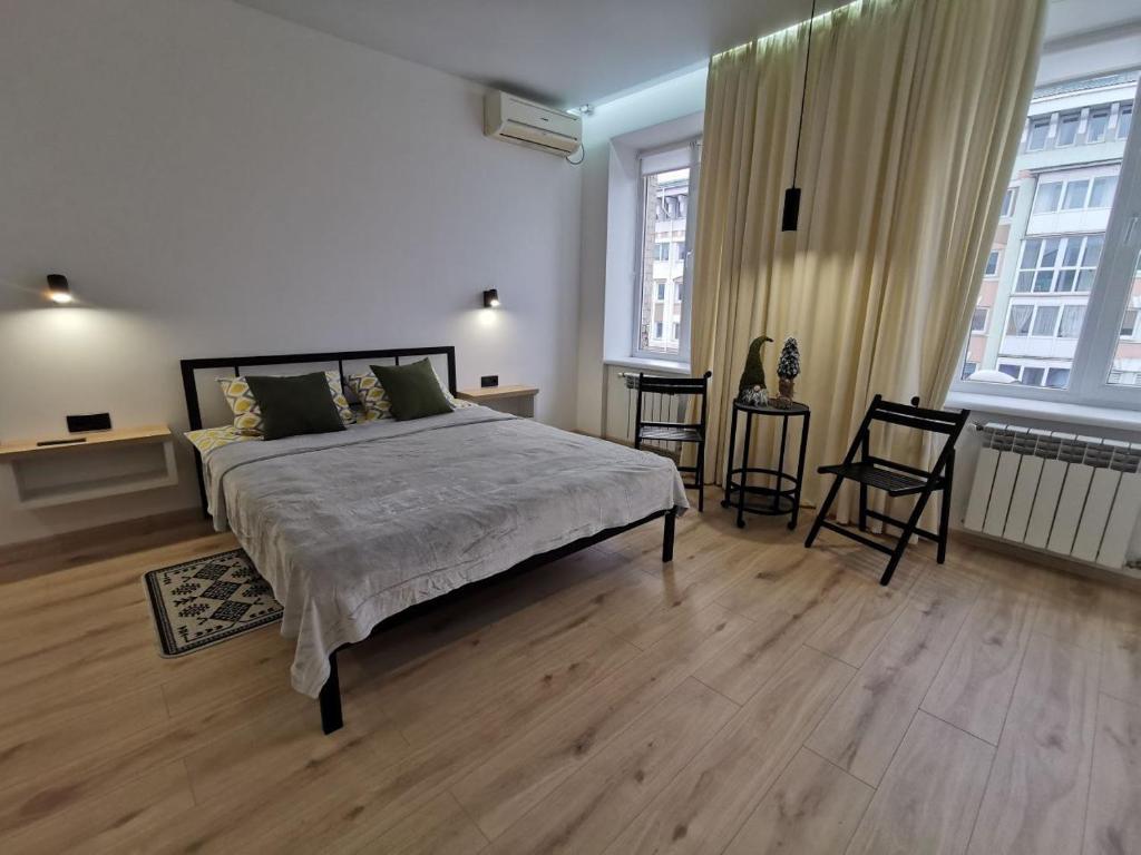 罗夫诺Soborna Apartment的一间卧室设有一张大床和两个窗户。
