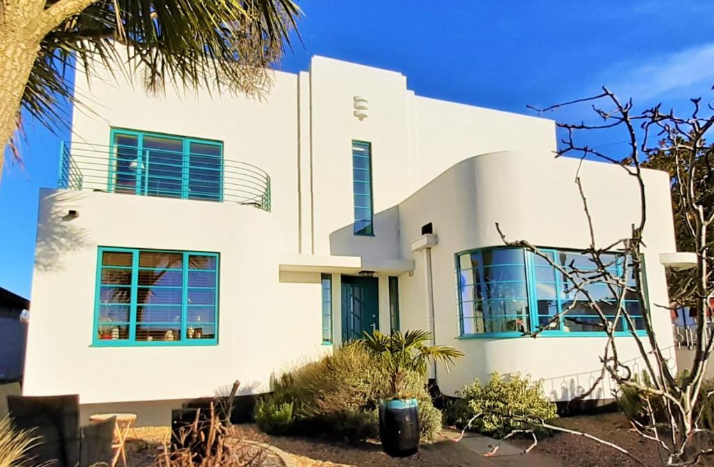 伯青顿Twentieth Century B&B的白色的房子,有蓝色的窗户和棕榈树