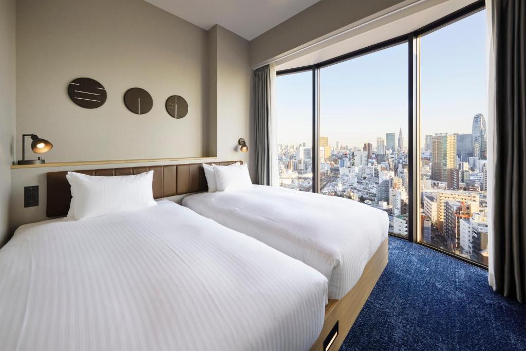东京东京新宿百日住宿的配有大窗户的酒店客房内的两张床