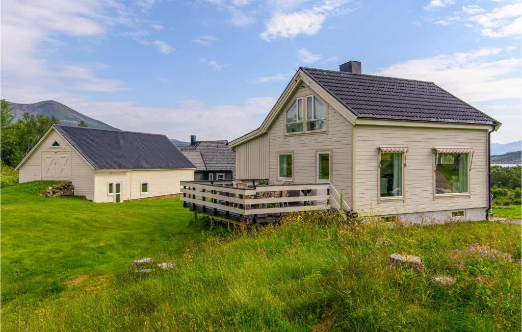 斯托克马克内斯Beautiful Home In Stokmarknes With House A Panoramic View的田野上带门廊的白色房子