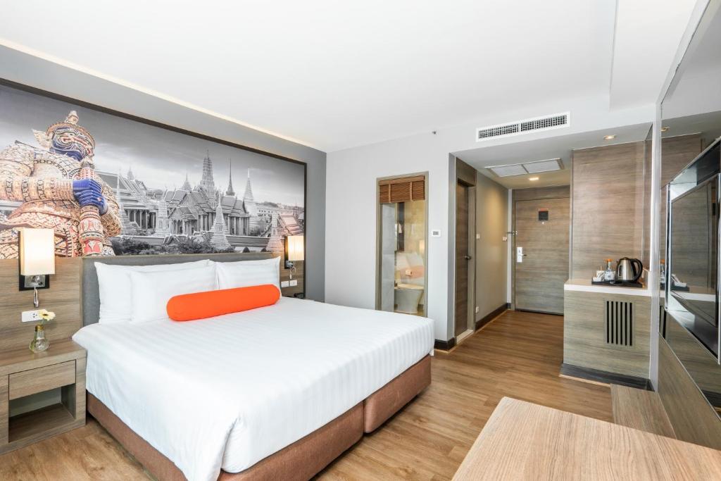 曼谷Citrus Sukhumvit 11 by Compass Hospitality的卧室配有一张大床,墙上挂有绘画作品