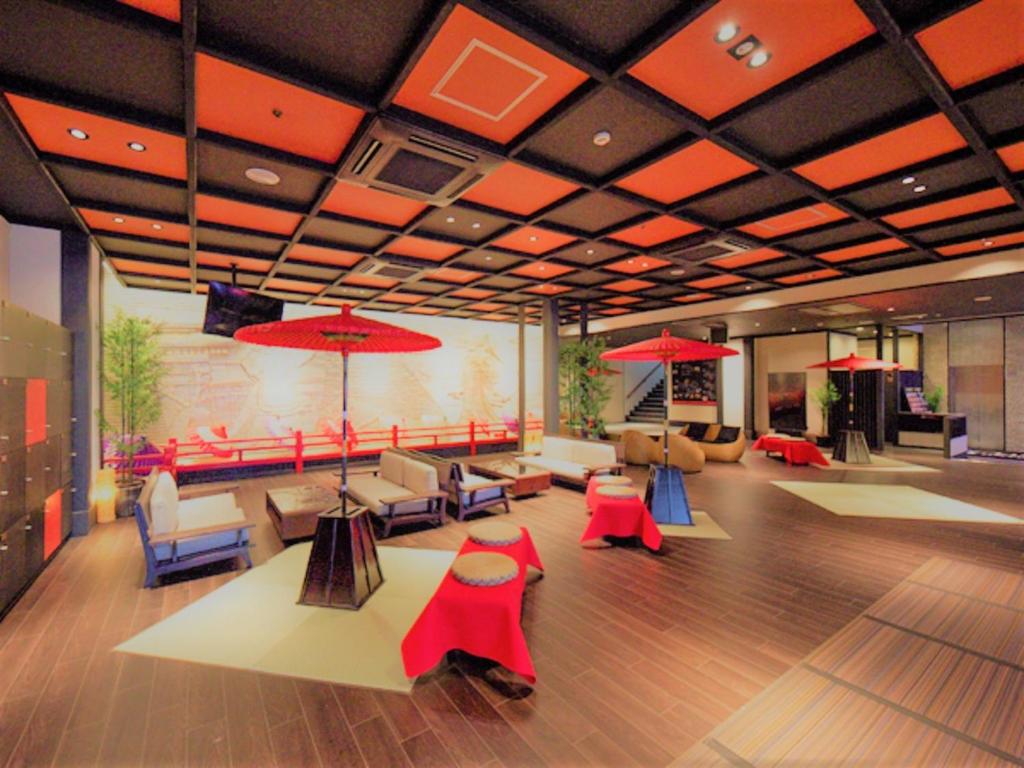 宫岛LiVEMAX RESORT Aki Miyajima的大堂设有桌椅和红色遮阳伞。