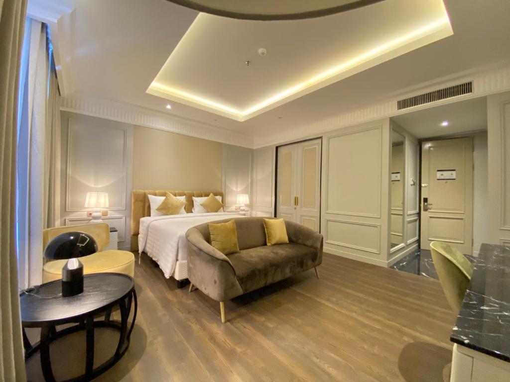 雅加达Maia Hotel Jakarta的一间卧室配有一张床、一张沙发和一张桌子