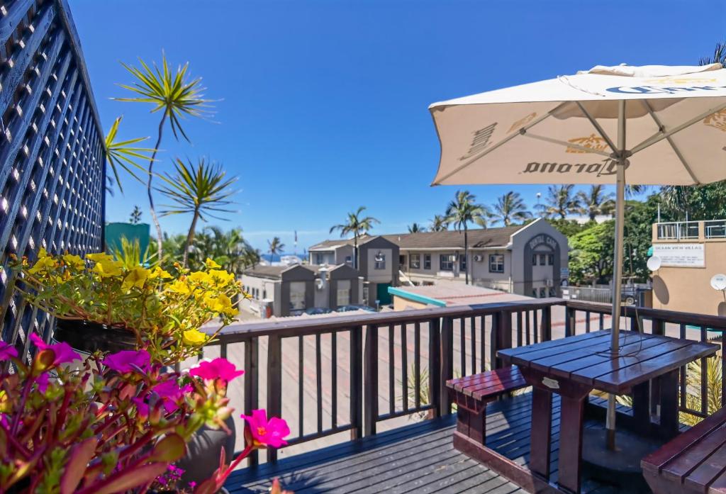 巴利托Ocean View Villas的一个带桌子、雨伞和鲜花的甲板
