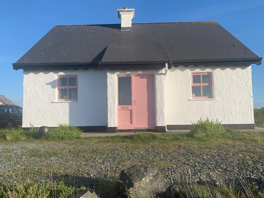 巴利康尼利Pink Cottage的一间白色的小房子,有红色的门