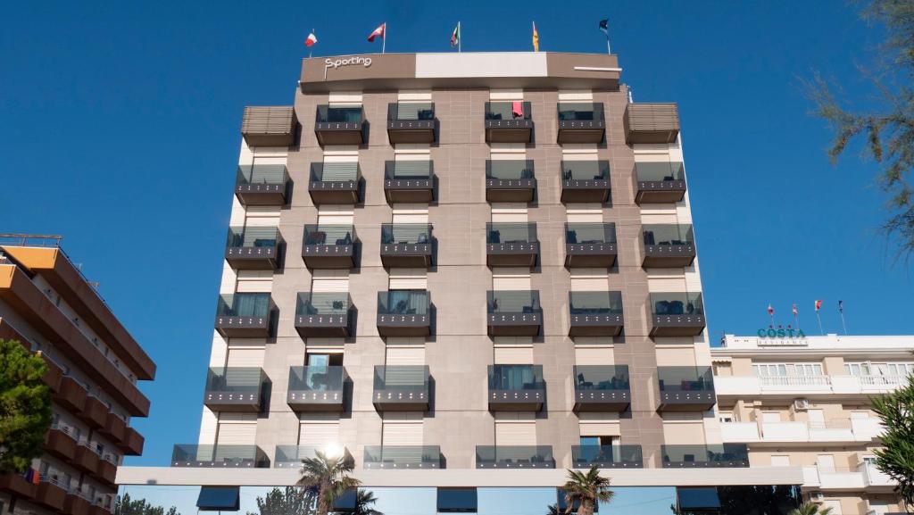 阿尔巴·阿德里亚蒂卡Hotel Sporting的一座高大的建筑,旁边设有阳台
