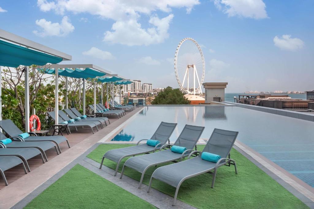 迪拜JA海景酒店 的一个带椅子和摩天轮的游泳池