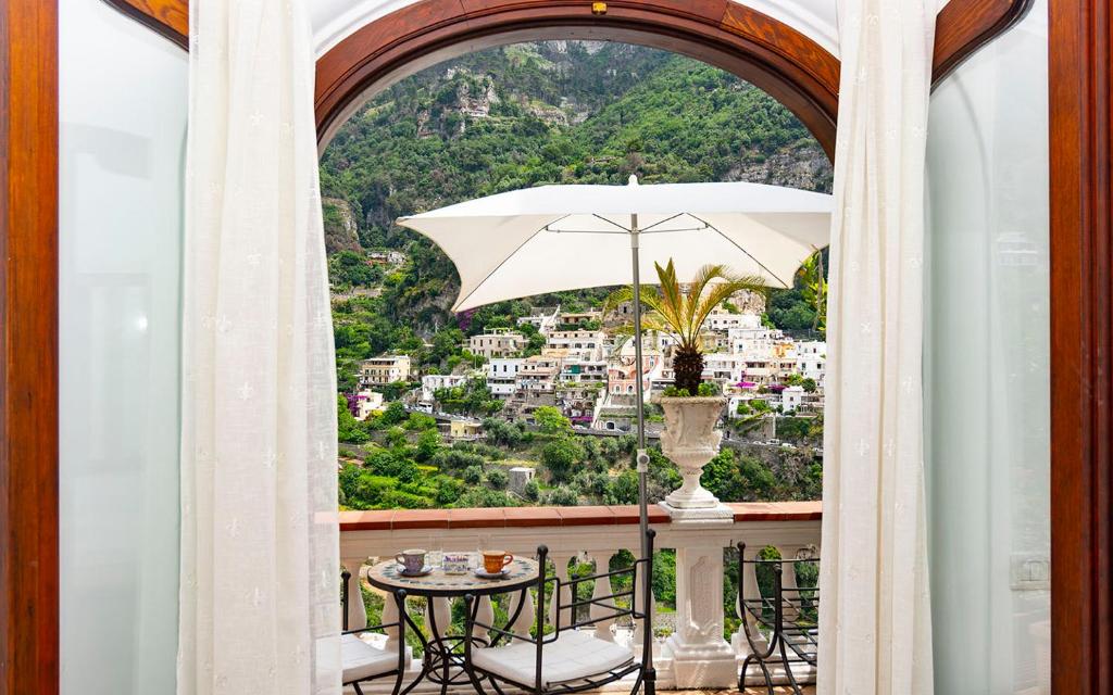 波西塔诺Villa Palumbo的阳台配有桌子和雨伞。