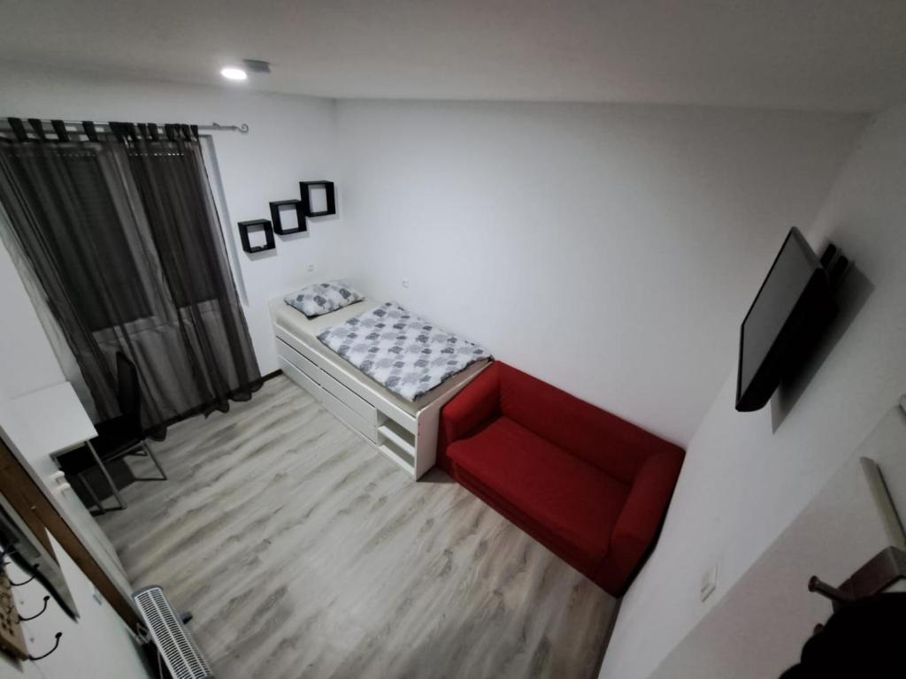 霍拉布伦HostelHollabrunn的客厅里有一张红色沙发和一台电视