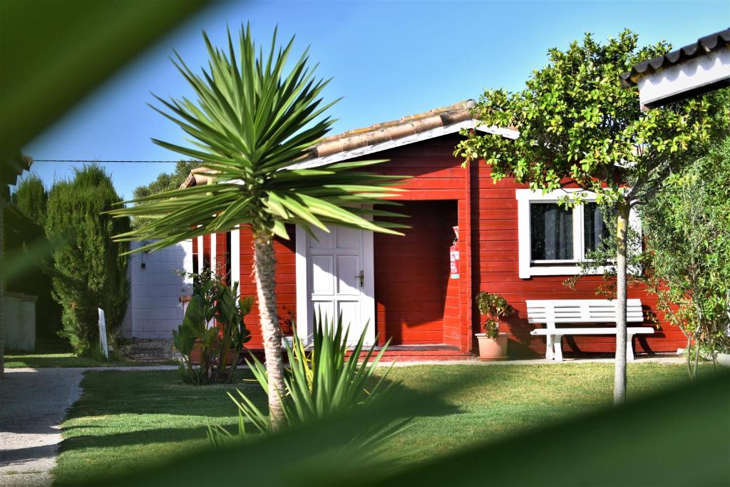 埃尔帕尔马Kontiki Bungalows El Palmar的红色的房子,有长凳和棕榈树
