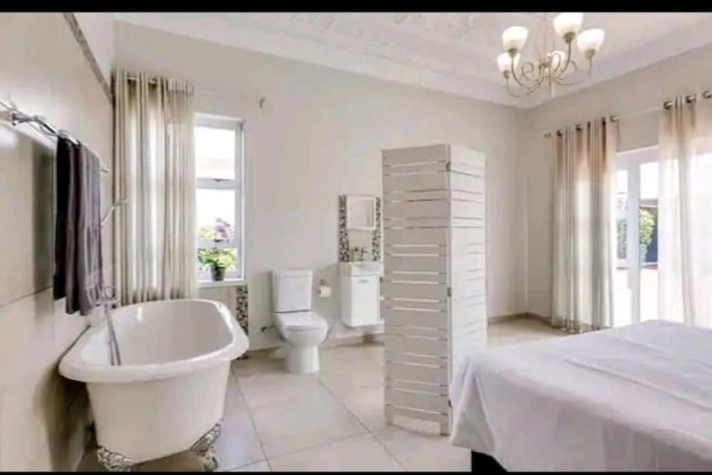 约翰内斯堡East Prestige lodge的白色的浴室设有浴缸、卫生间和水槽。