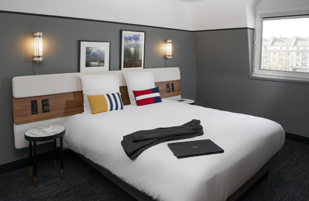 凯恩凯恩中心普莱森斯门美居酒店的一间卧室配有一张白色大床,上面有笔记本电脑
