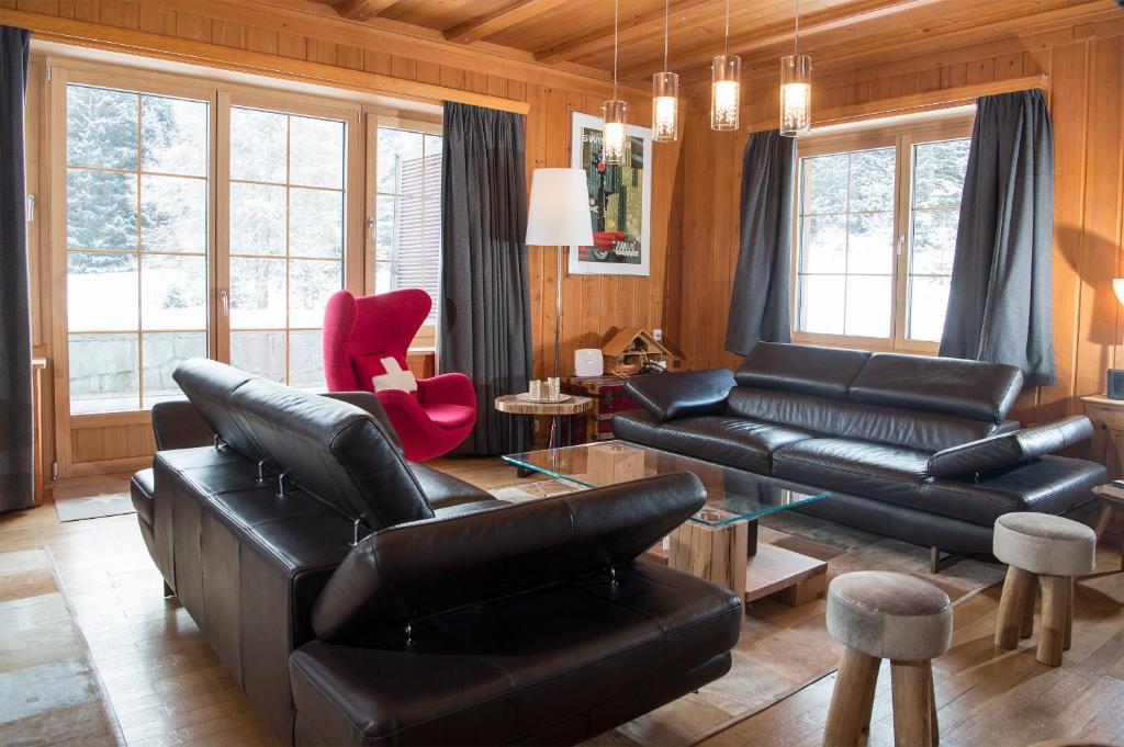 伦策海德Residence for 12 persons Chalet Crestas-Lenzerheide的客厅配有黑色皮革家具和窗户。