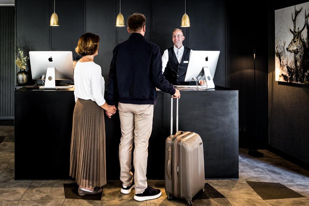 格罗斯梅克森施罗德酒店&餐厅的男人和女人站在柜台上,拿着手提箱