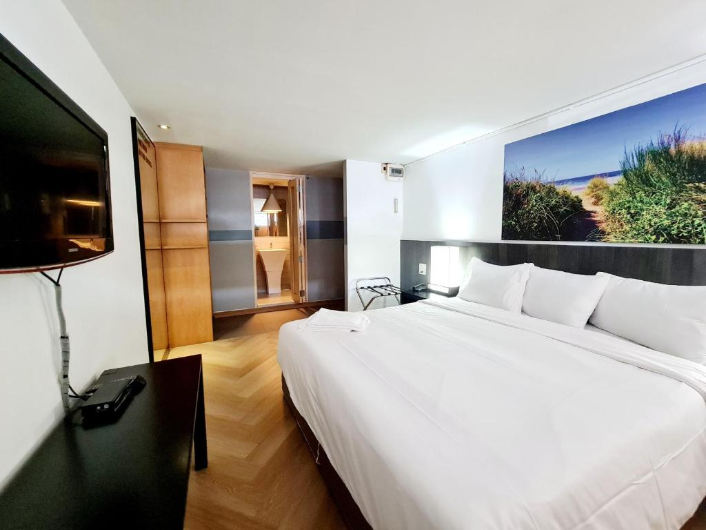 曼谷Somewhere to Escape - Hometel的卧室配有一张白色大床和一台平面电视。