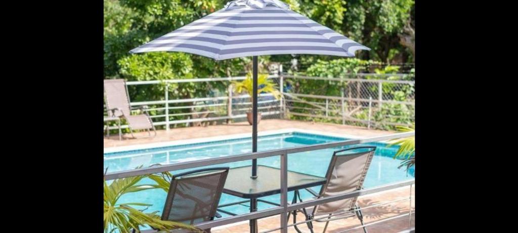 蒙特哥贝Hills Royale Villa -Ironshore Montego Bay的游泳池旁的蓝白遮阳伞