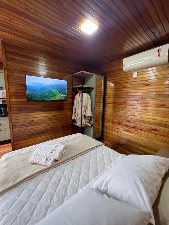 邦雅尔丁-达塞拉Recanto da Maju的一间卧室设有一张床,木墙上配有电视。