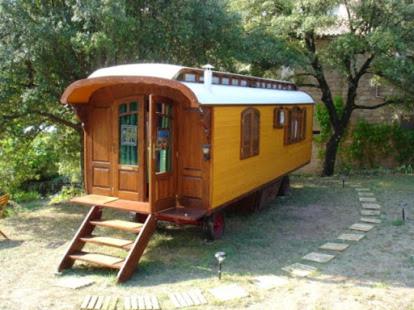 Les AssionsIdyllic Roulotte的坐在院子里的小黄火车车厢