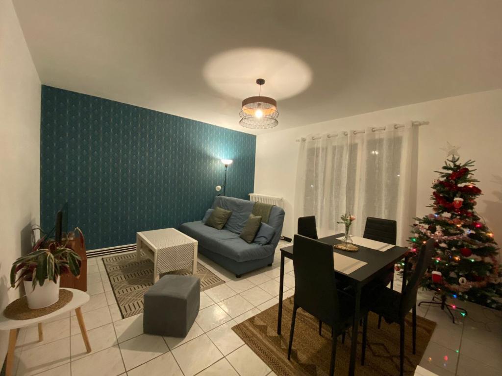 圣皮耶尔代科尔普Appartement cosy près de la gare avec parking的客厅配有圣诞树和蓝色沙发