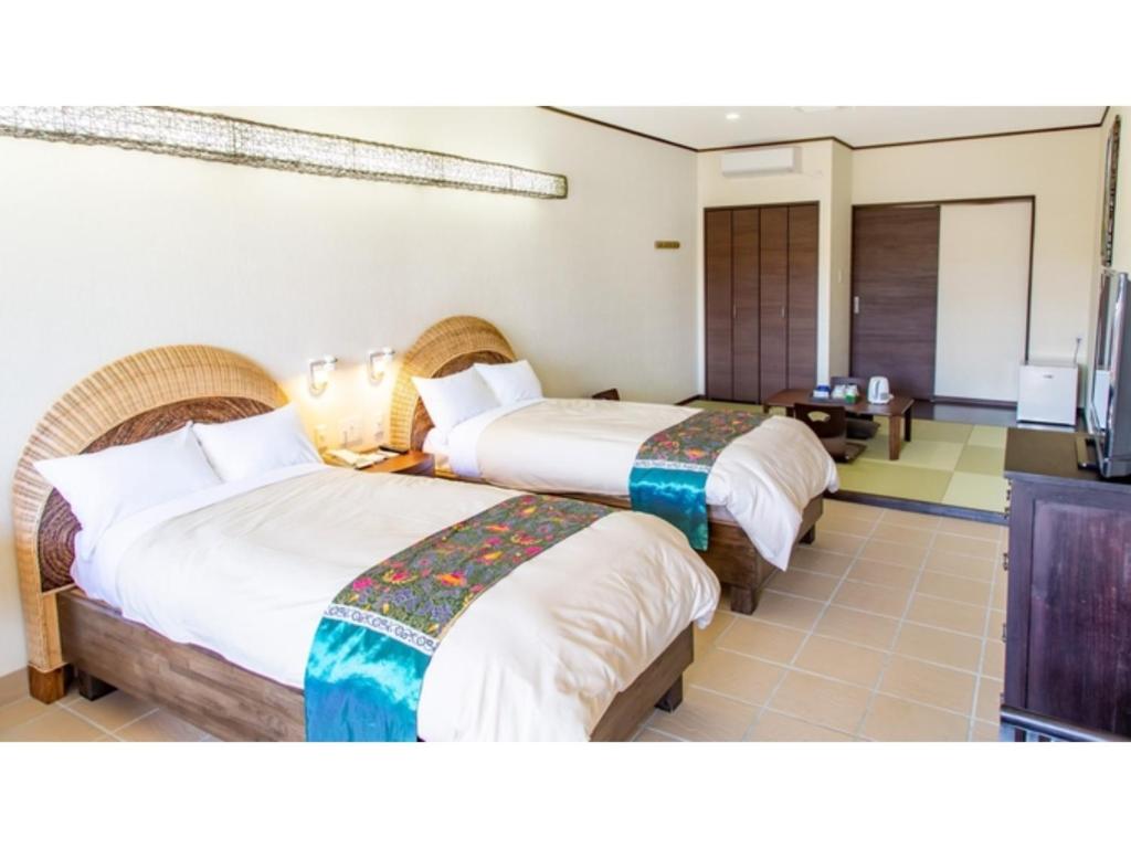 MitsuneHachijojima Hotel Resort Sea Pillows - Vacation STAY 53316v的酒店客房设有两张床和电视。