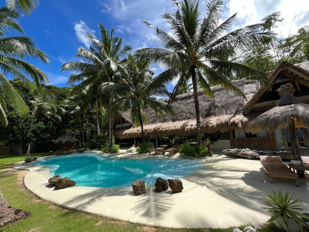 布桑加The Beach House Ocam Ocam的棕榈树游泳池度假村