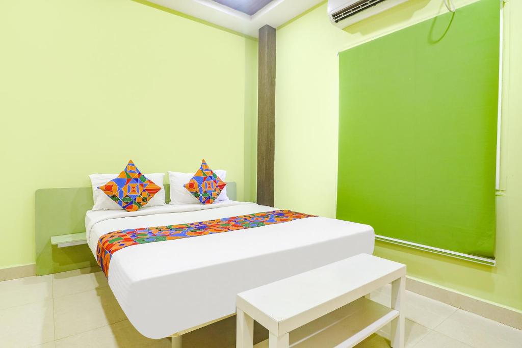 海得拉巴FabExpress Airport Stay Inn的绿色墙壁的房间里一张白色的床