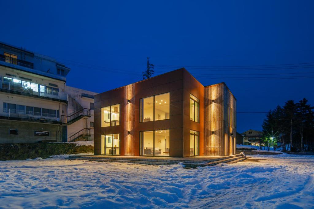 白马村Bluebird Apartments by The Hakuba Collection的一座大建筑物,在晚上下雪