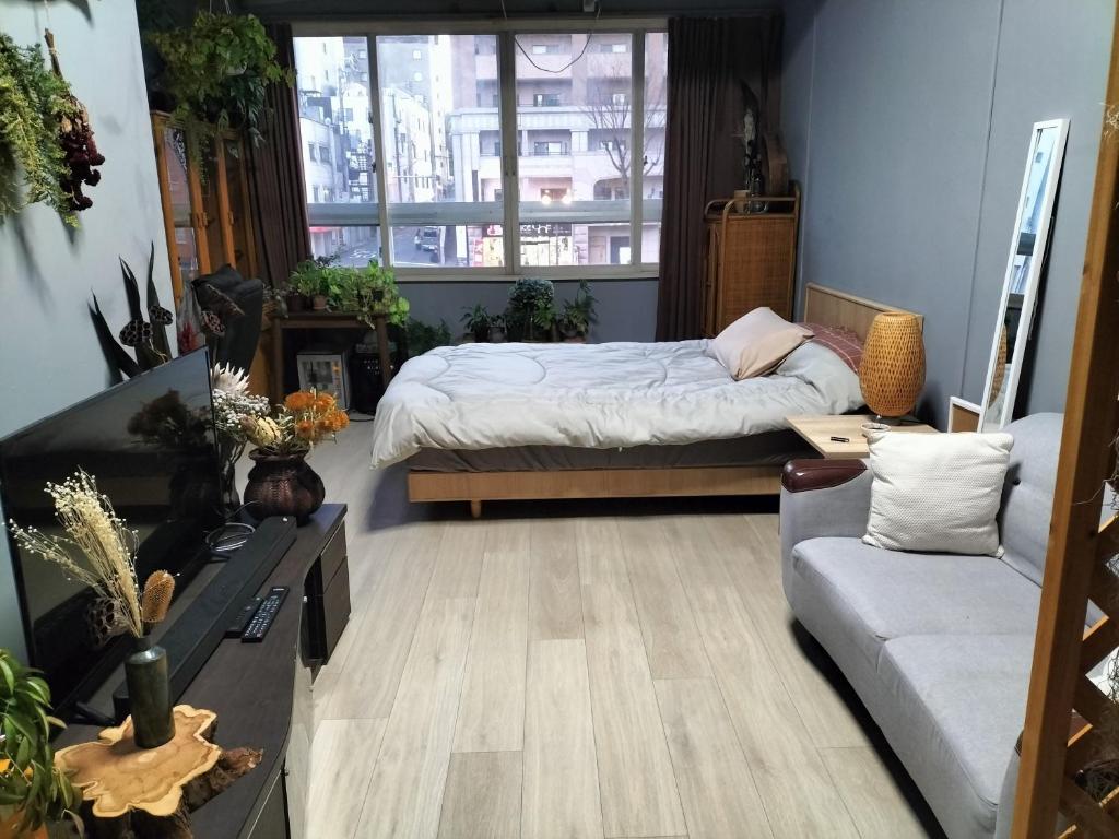 大阪Backstage Party Hostel & Bar的一间卧室配有一张床和一张沙发